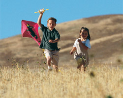 Childen running, flying a kite